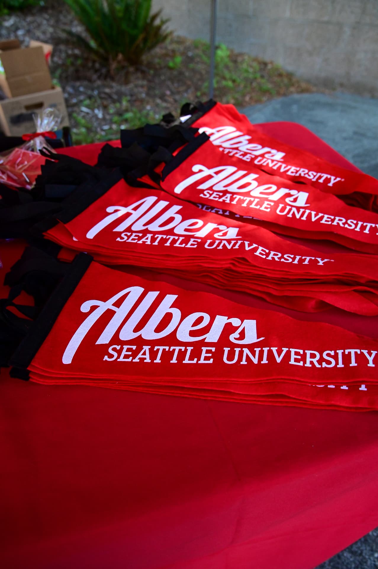 Stacked red Albers Seattle University tote bags on an event table